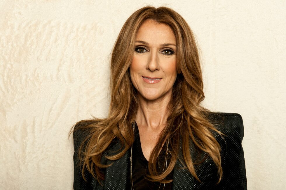 Celine Dion smiling on stage, announcing her Paris concert return after the Olympics