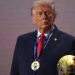 Donald Trump holding the golden eagle 'America First Award' presented by House Speaker Mike Johnson at a GOP fundraiser