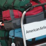 American Airlines baggage claim area with new fee increase signage for basic economy passengers