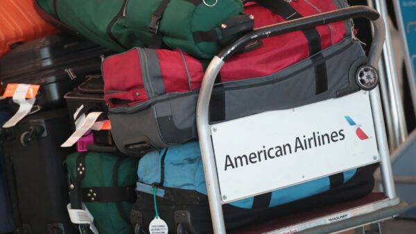 American Airlines baggage claim area with new fee increase signage for basic economy passengers
