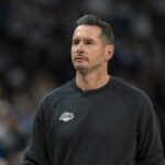 Lakers coach JJ Redick and Luke Kennard discuss strategy on the sideline during an NBA game.
