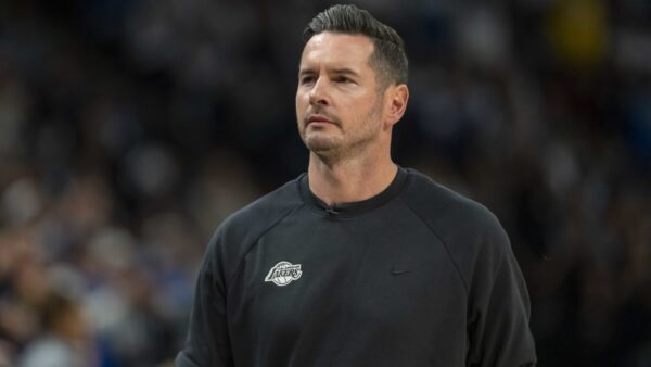 Lakers coach JJ Redick and Luke Kennard discuss strategy on the sideline during an NBA game.
