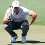 Rory McIlroy swinging a golf club while leading the 2026 Masters Tournament at Augusta National