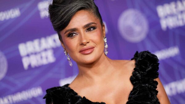 Salma Hayek showcasing her natural gray hair in a sheer black Gucci gown on the red carpet at the Breakthrough Prize ceremony